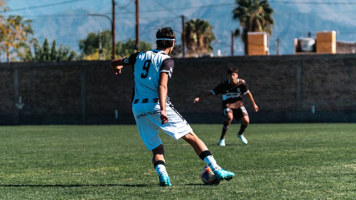 Two soccer players in dynamic motion during an outdoor match on a sunny day.